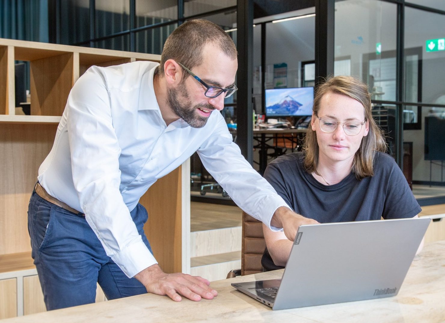 Mitarbeiter und Mitarbeiterin im Austausch über ein Thema am Laptop