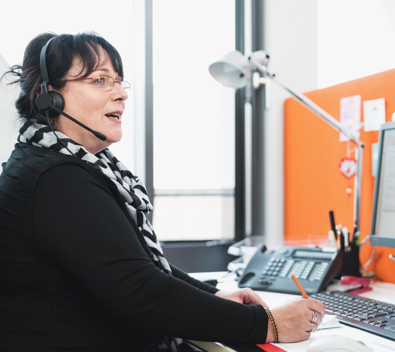 Das Bild zeigt eine Service-Mitarbeiterin im Gespräch an der Kundenhotline von PostModern.