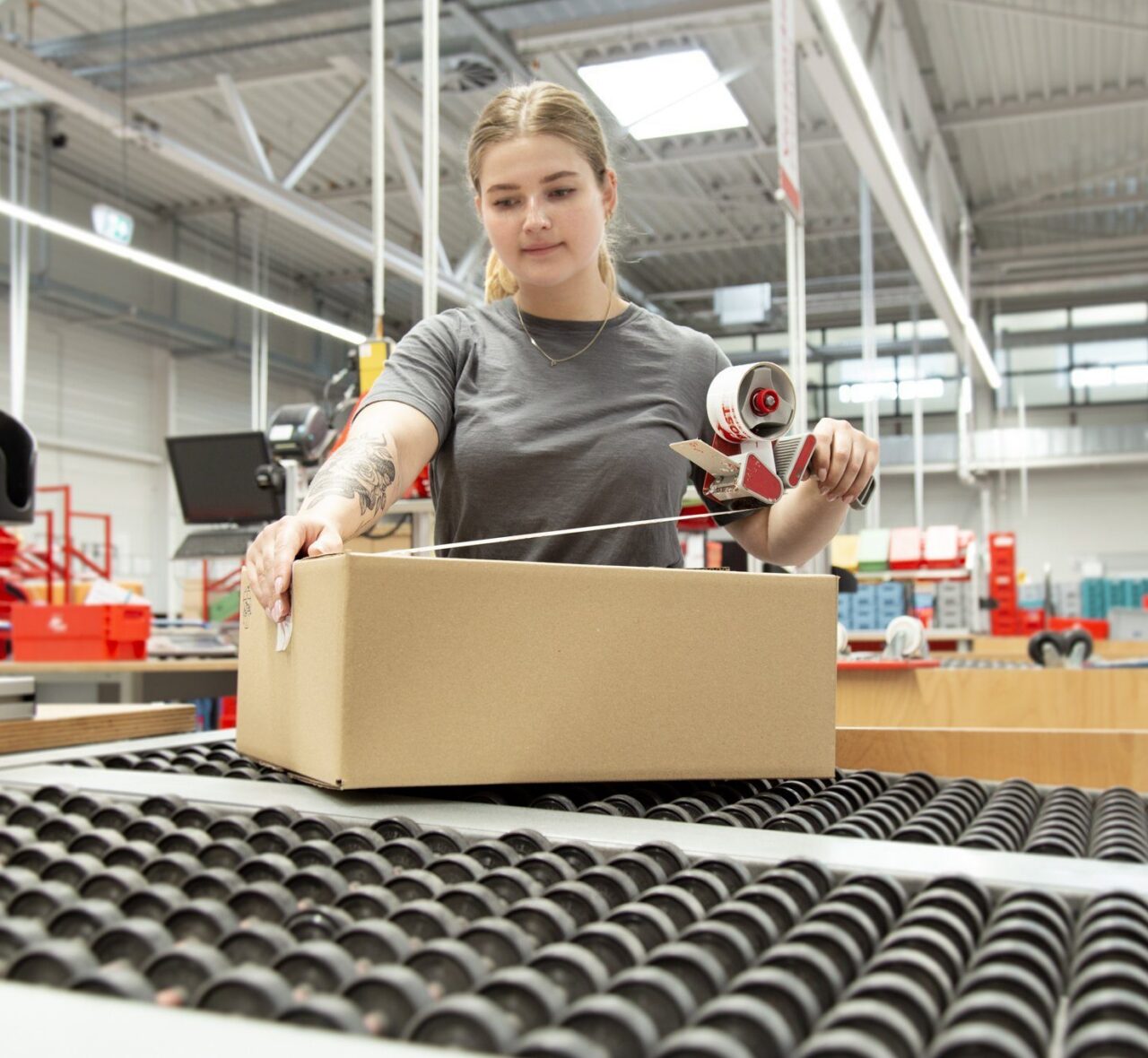 Das Bild zeigt eine Mitarbeiterin von PostModern packt ein Paket für einen Geschäftskunden.