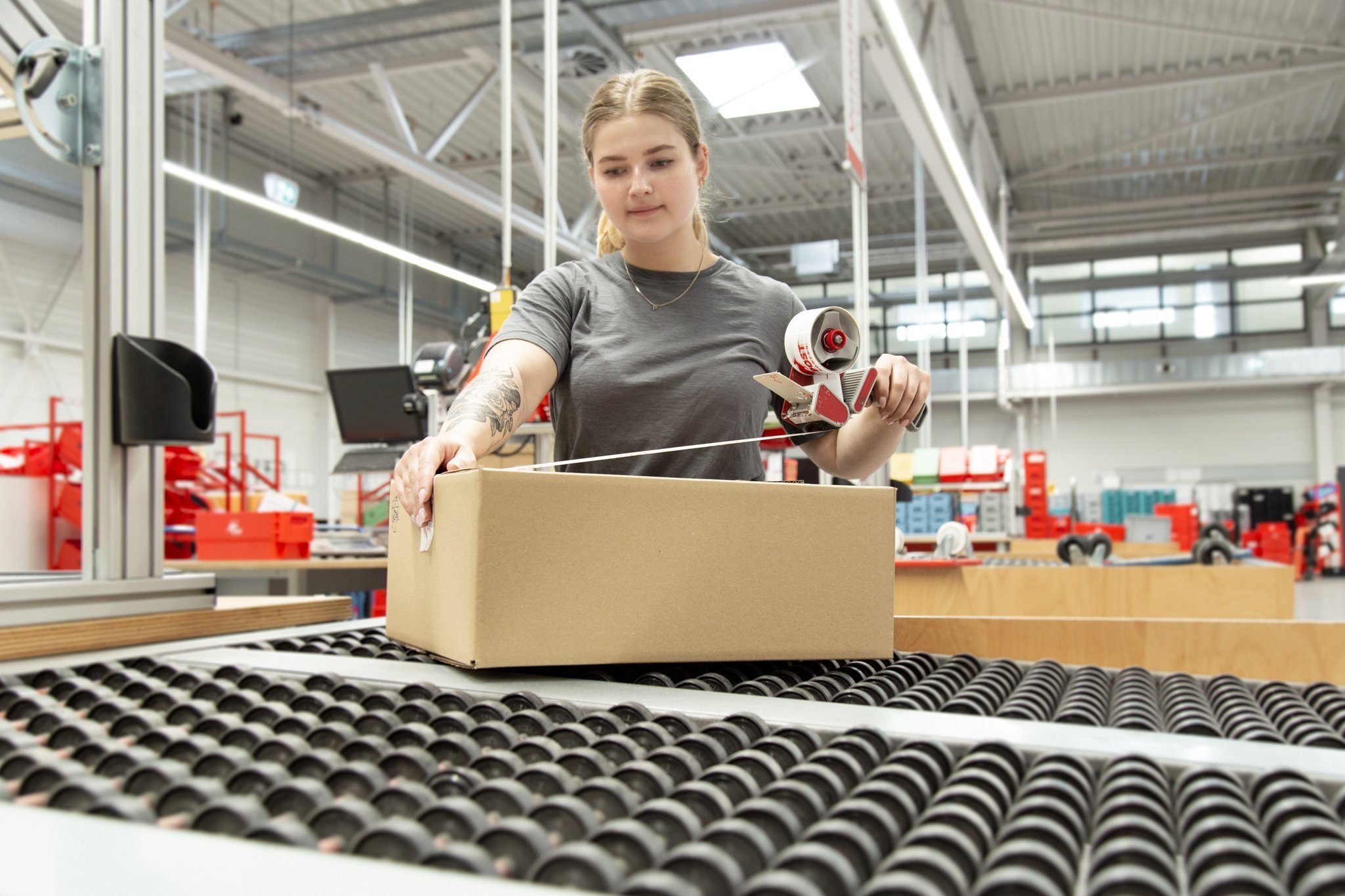 Mitarbeiterin von PostModern packt ein Paket für einen Geschäftskunden